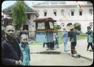 Men carrying a sedan chair amid bystanders, China, ca.1917-1923