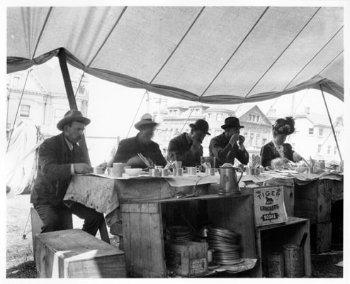 [Five people eating at a restaurant in a refugee camp]