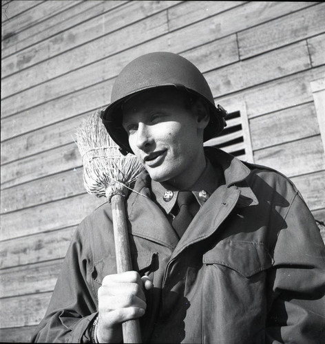 Helmeted soldier holding a broom