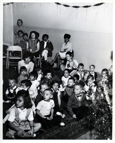 Large group of children sitting around a Christmas tree