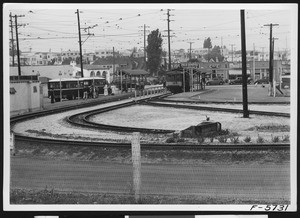 Pico Boulevard bus terminal, with buses and a trolley car, April 12, 1937