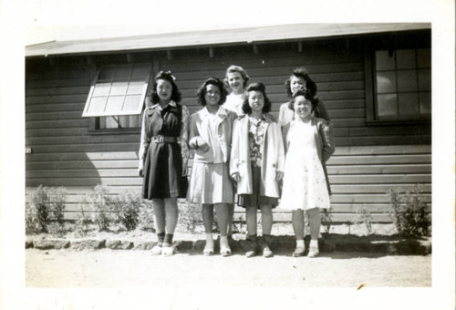 [Women pose in front of building]