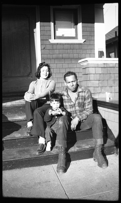 Man, woman and boy sitting on front steps of house