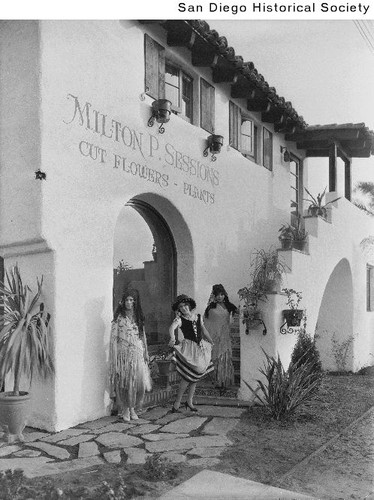 Three women in Spanish attire posing in front of Milton P. Sessions' flower shop in Old Town