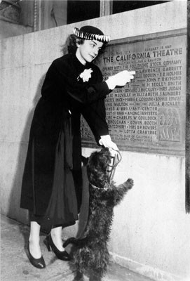 [Edith Barrett standing in front of a plaque commemorating the California Theatre]