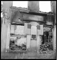 [Saint Dié, Vosges: American flags hung on ruined building with a plaque commemorating historic cartographer Martin Waldseemüller (who first placed the name "America" on a map)] (Mis-filed with Puget-Théniers series.)