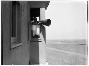 Man using a bull horn in the window of the Marine Exchange in San Pedro