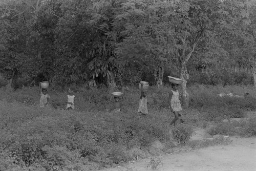 Girls walking with metal container on their head, San Basilio de Palenque, 1976