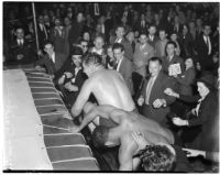 Wrestlers Gino Garibaldi and Ernie Dusek falling out of the ring during at match a Olympic Auditorium, Los Angeles, October 6, 1937