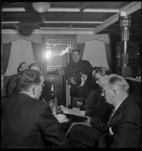 On Ship, afernoon. Capt. Hugo Dahlblom in background [SS Kastelholm. Evacuation of Americans] [Men listening to radio and reading news]