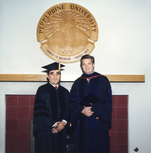 Jose Collazo and President Davenport standing in front of the Pepperdine University Seal