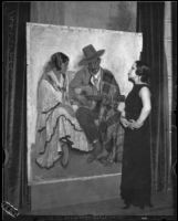 Artist Maroussia Valero standing before her painting of a seated Spanish couple with the man playing a guitar, circa 1932