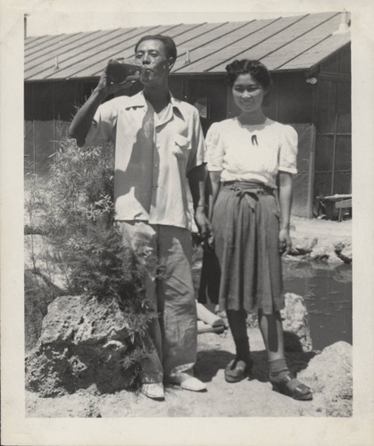 Man and woman holding hands pose in front of pond at Poston incarceration camp