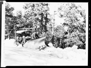 Man attending to the shovel of a snow plow in Big Pines Recreational Camp, 1928