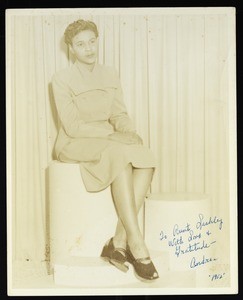 Andrea Mallory, sitting wearing a dress and shoes with toes out, ca. 1952
