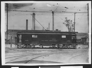 Pacific Electric railway car sitting on tracks near buildings and columns, ca.1912