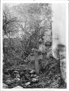 Cross marking a grave in a neglected corner of the cemetery at Mission San Gabriel Arcangel, ca.1900