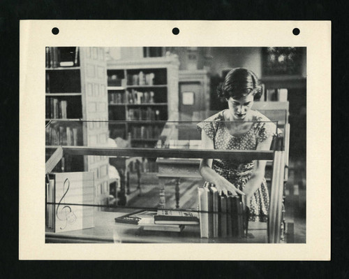 Student librarian arranging books in a display case in Denison Library, Scripps College