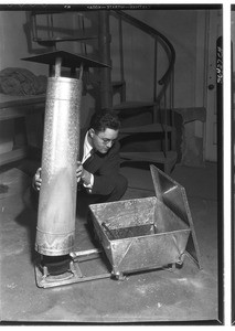 Andrew Boone making adjustments to a smokeless oil heater, January 1933