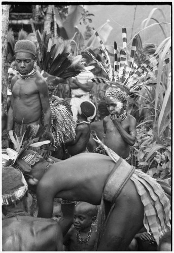 Bride price ritual: feeding blood pudding to bride's kin, including decorated child (probably a child of the bride and groom)