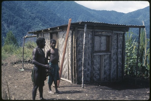 Small tin-roofed tradestore, Wando and another man