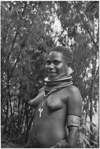 Courtship: smiling adolescent girl wears shell valuables, trade beads, and other finery (including keys on ring), ready for courtship event