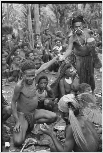 Bride price ritual: crowd at exchange, man distributes pork provided by groom's group