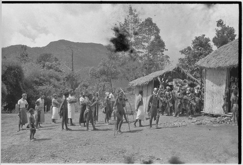 Returned laborers (in western clothing), their kin inspect new-style house built by the returnees