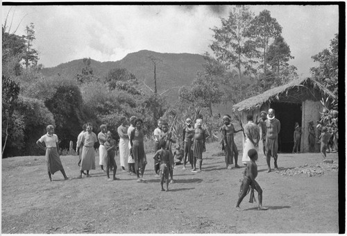 Returned laborers (in western clothing), their kin inspect new-style house built by the returnees