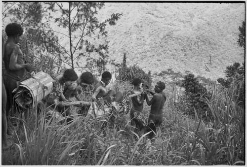 Mortuary ritual: women, their faces and bodies smeared with clay as sign or mourning, carry corpse wrapped for burial