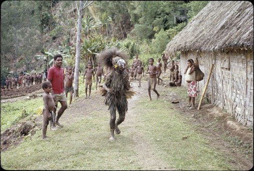 Ery Ben, dressed in leaves and mud, clowns with local children