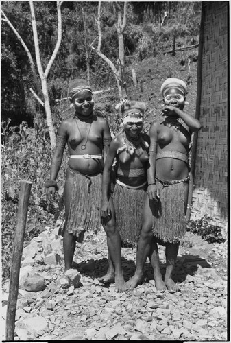 Adolescent girls (Kopi, Kanila, and Kena) laughing, next to Cooks' house in Kwiop