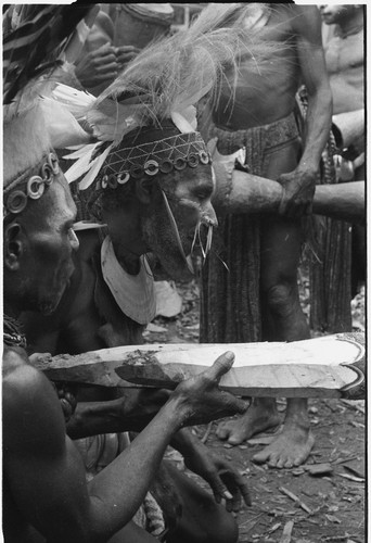 Pig festival, pig sacrifice preparations: Kolip and Kent blow spells on gate posts for ritual fence through which allies will be fed