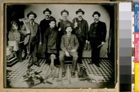 China Town Squad in 1898. L. to R. Standing - Phil Herrin - D. Campbell - D. Lyons - A. Say - M. Griffin. The Chinaman is Dong Gong or Dong Tying the Interperter [sic], and Sergt. Jas. Donovan - with Opium Pipe and Layout on the floor