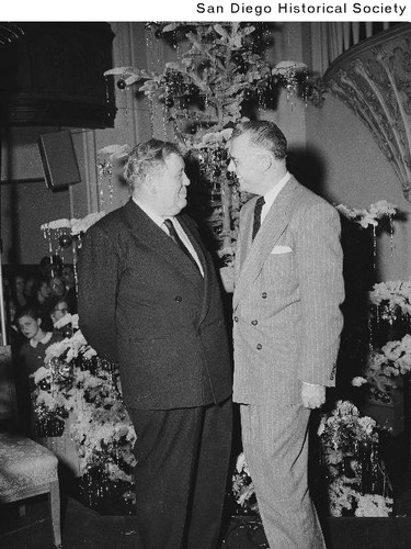 Charles Laughton standing in front of a Christmas tree with George Scott