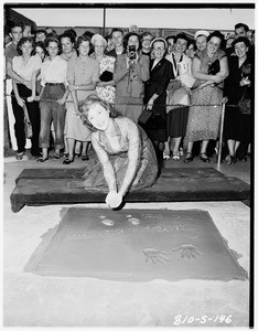 Susan Hayward putting footprints in cement at Grauman's Chinese Theater, 1951