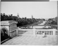 Child crouched on a balustraded terrace looking out at a pool at the Jardin d'Essais, Algiers, 1929