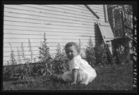 Baby Rosita Dee Cornell sitting outside by the side of a house, California, 1932