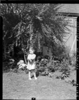 Three-year-old Rosita Dee Cornell standing outside holding something in her outstretched hands, California, 1934