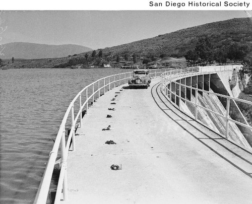 An automobile driving across the Lower Otay Dam