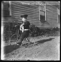 Young boy on tricycle wearing sailor suit