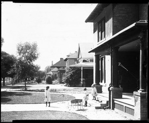 Three children playing with a wagon in front of a house in Phoenix, Arizona