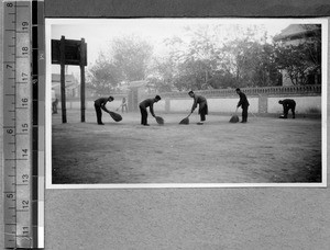 Sweeping the athletic area at Harwood Bible Training School, Fenyang, Shanxi, China, ca.1936-37