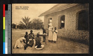 Missionary sister administering medical treatment outside a brick building, Congo, ca.1920-1940
