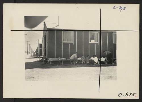 Manzanar, Calif.--Evacuees at this War Relocation Authority center relaxing in the shade of their barrack apartment. Photographer: Lange, Dorothea Manzanar, California