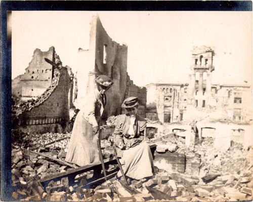 [Two women posing among ruins of a building]