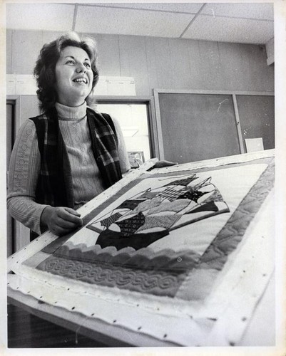Woman standing next to a quilted project