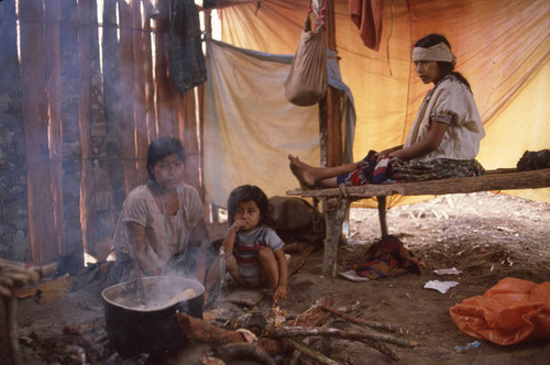 Guatemalan refugees sit inside a hut, Chajul, ca. 1983