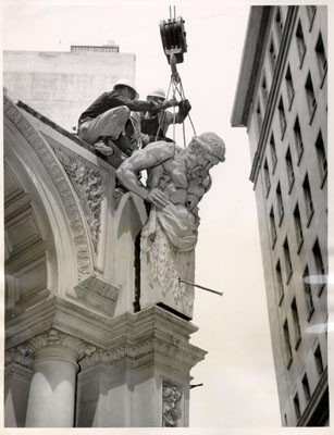 [Workmen removing a molded torso of a Greek mythological figure from the exterior of the American Trust Company]
