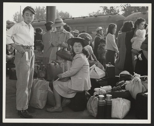 Families of Japanese ancestry with their baggage at railroad station awaiting the arrival of special train which will take them to the Merced Assembly Center about 125 miles away. Woodland, California